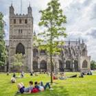 People relaxing on the green in front of Exeter Cathedral, Devon, England.