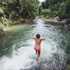 High angle view of carefree woman jumping into lake amidst forest in Costa Rica