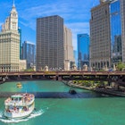 A boat on the Chicago River passes beside landmark Chicago buildings, USA.